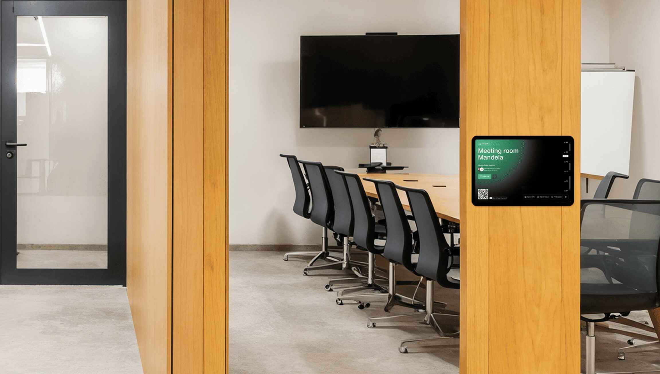 Modern meeting room with a wall-mounted room booking display showing availability for “Meeting room Mandela.”