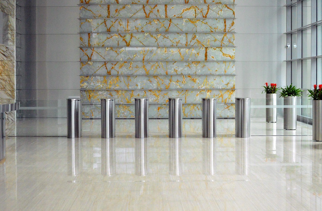 A modern building lobby with a sleek security entrance featuring metal turnstiles.