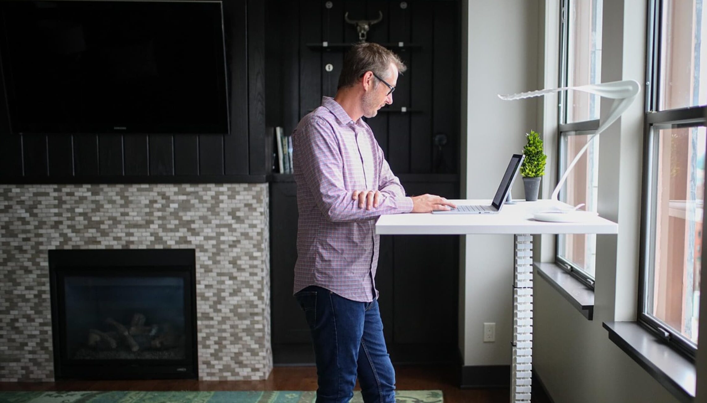 A man working at a laptop in a modern, open office space with other people in the background.