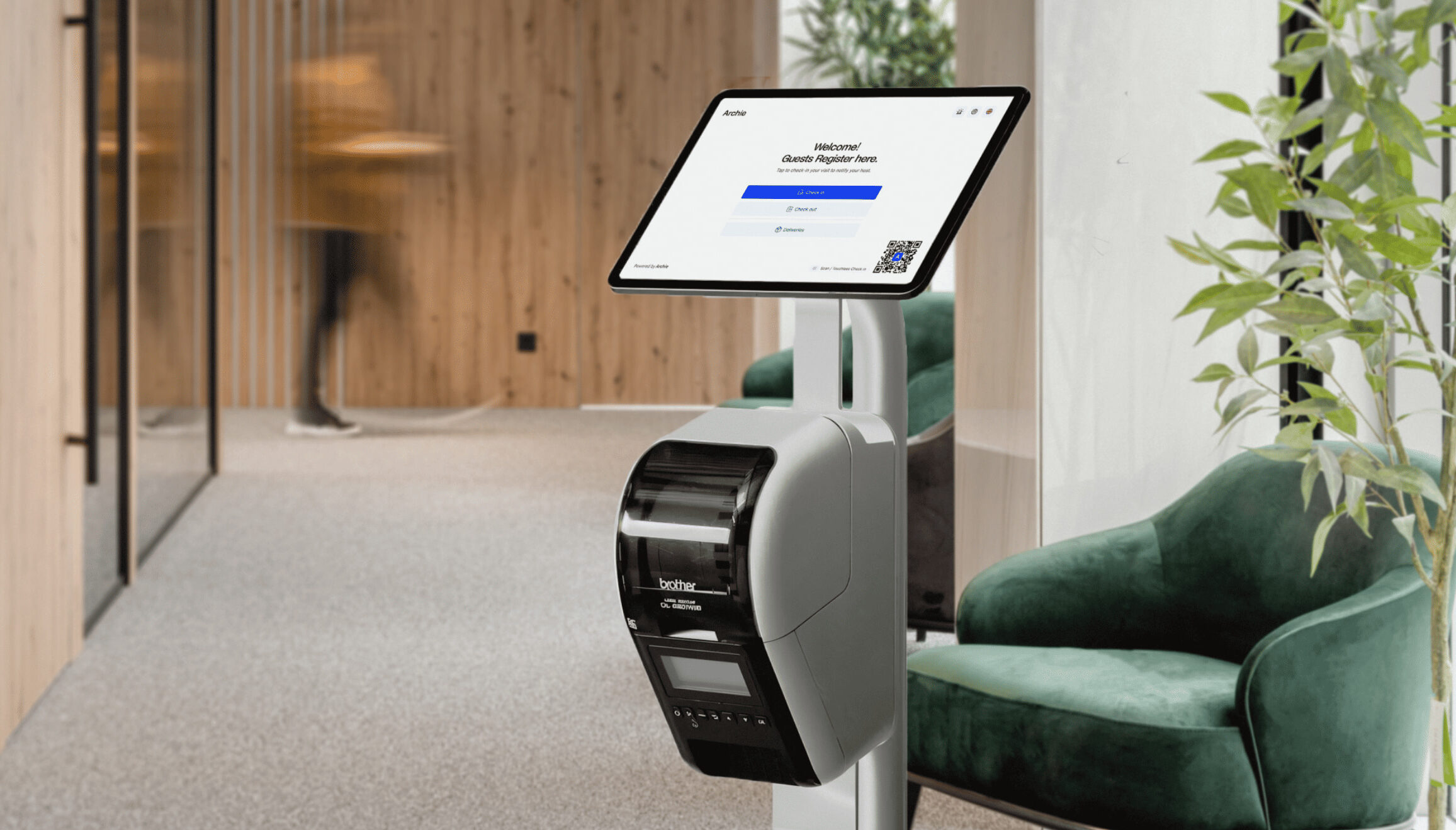 Archie's digital check-in kiosk with a touchscreen and badge printer set up in a modern office lobby, displaying a guest registration form.