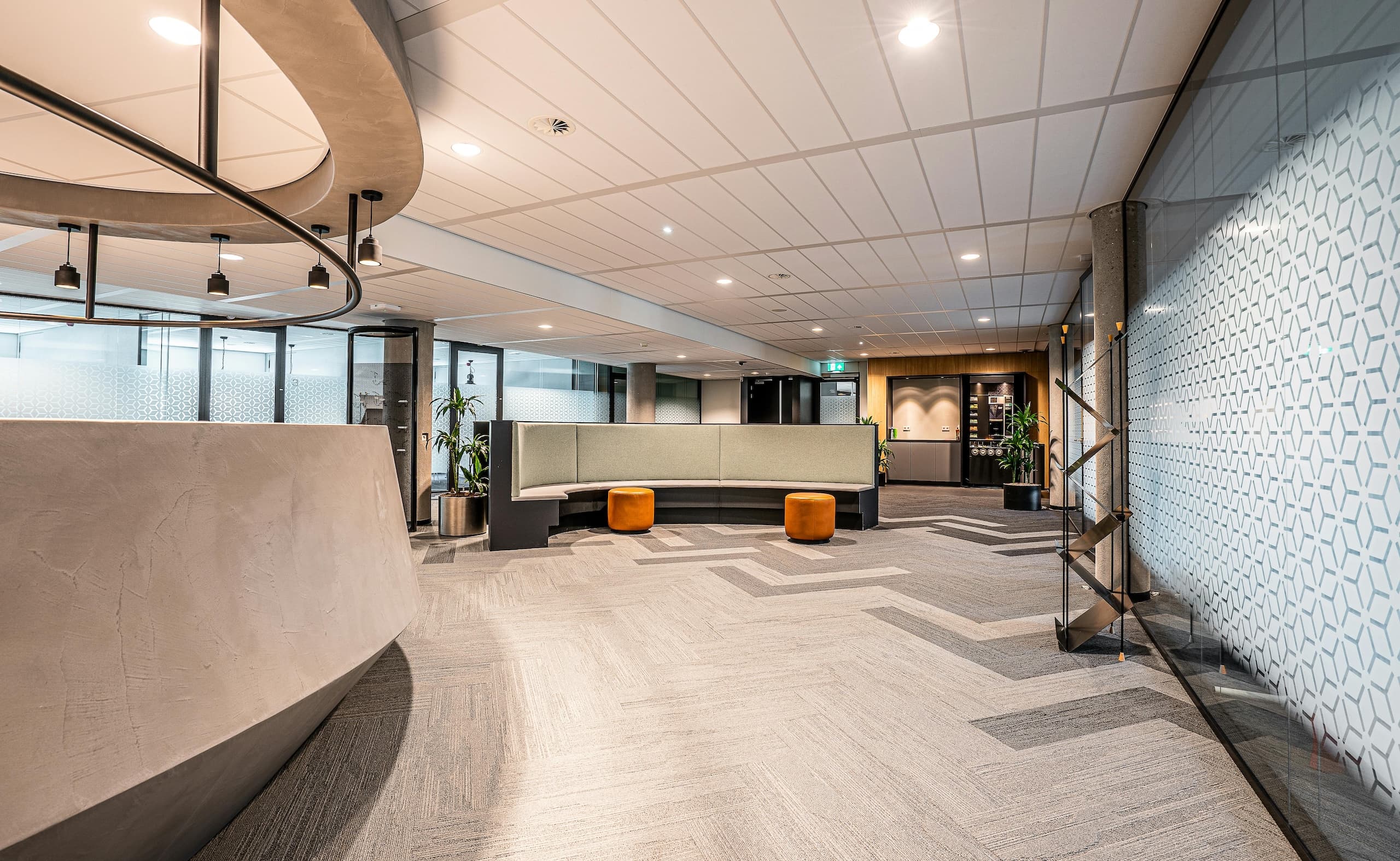 Modern office lobby with curved seating, soft lighting, and a clean, open layout.