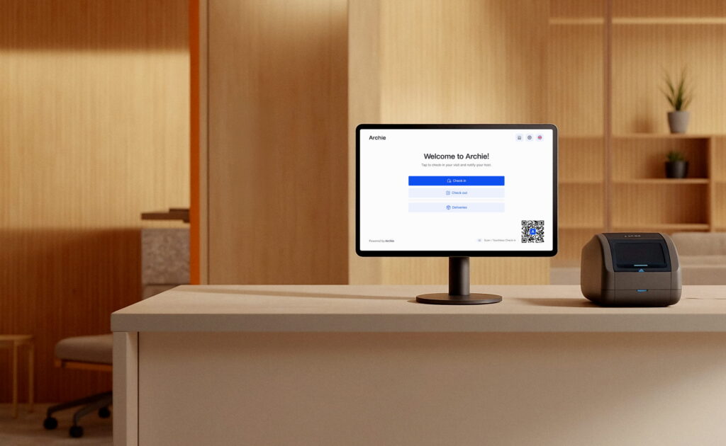 Reception desk running Archie’s visitor check-in app and badge printer in a modern office lobby.