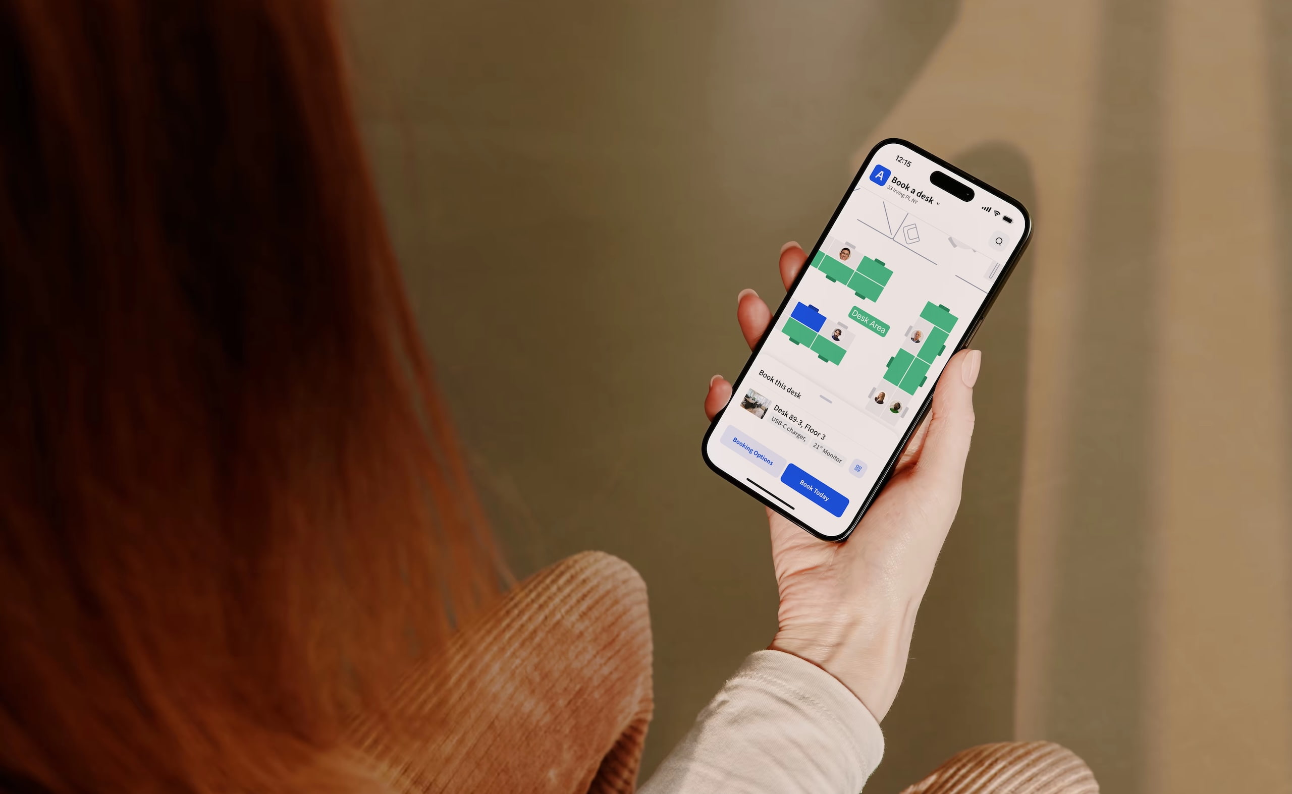 Person holding a smartphone using Archie desk booking app with an office floor plan.